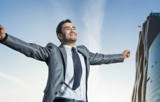 Successful businessman with his arms wide open. Joyous man with success perspective, modern buildings at background