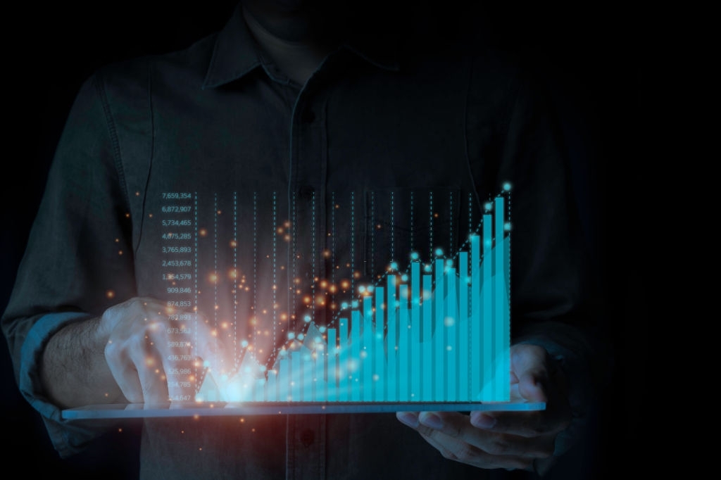 A male businessman is standing by a tablet analysing the ongoing upwards of the graph. A rapidly changing business concept on a black background.
